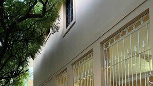 Un edificio con tres grandes ventanales adornados con celosías metálicas.