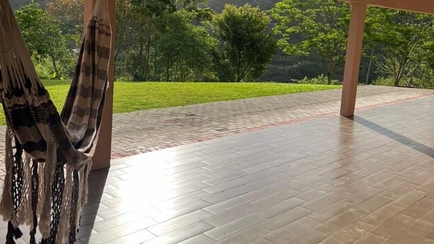 Una hamaca bajo un porche cubierto con vistas a un paisaje verde.