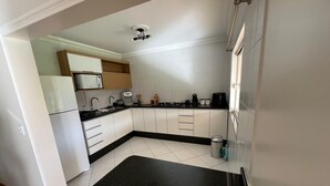 Una cocina compacta con armarios blancos, una encimera negra y un microondas integrado.