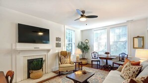 A living room with a fireplace, television, and comfortable seating. - Luxury Stay in a Restored 1920s Savannah Home (Savannah)