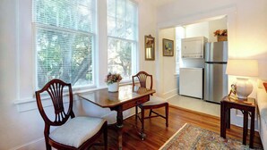 A dining area with a wooden table and chairs, a small rug, and a kitchen visible through an open doorway. - Luxury Stay in a Restored 1920s Savannah Home (Savannah)