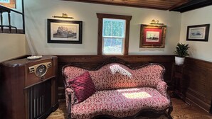 A room with a vintage sofa, wooden paneling, and framed pictures on the walls. - Jasper Short Line
1968 Train Caboose (Jasper)