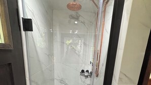 A glass-enclosed shower with a rain showerhead, a handheld showerhead, and a black handheld showerhead on the floor. - Jasper Short Line
1968 Train Caboose (Jasper)