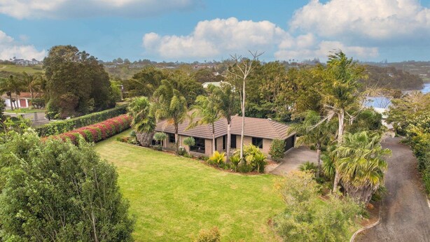 Uma casa com um gramado bem cuidado, rodeada por árvores e um jardim.