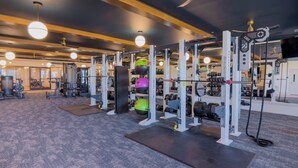A gym with various exercise equipment, including weight machines and free weights, arranged on a carpeted floor. - Funky 1 Bedroom in 5 Points. State of the Art Gym. Long Term Stays Welcome (Birmingham)