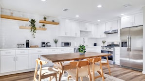 Una cocina moderna con armarios blancos, encimeras de madera y una isla central con sillas.