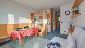 Un espace de vie compact comprenant un coin repas, une kitchenette et un coin salon confortable.