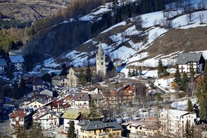 A town with a prominent church, surrounded by residential buildings and snow-covered hills. - La Casa Di Mitti, Cesana Torinese, Italy (Cesana Torinese)