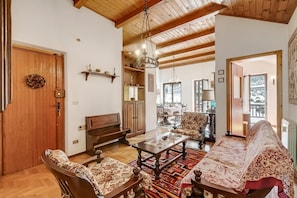 Un salon spacieux doté d’un plafond en bois, d’une cheminée, d’un coin repas et offrant une vue sur l’extérieur.