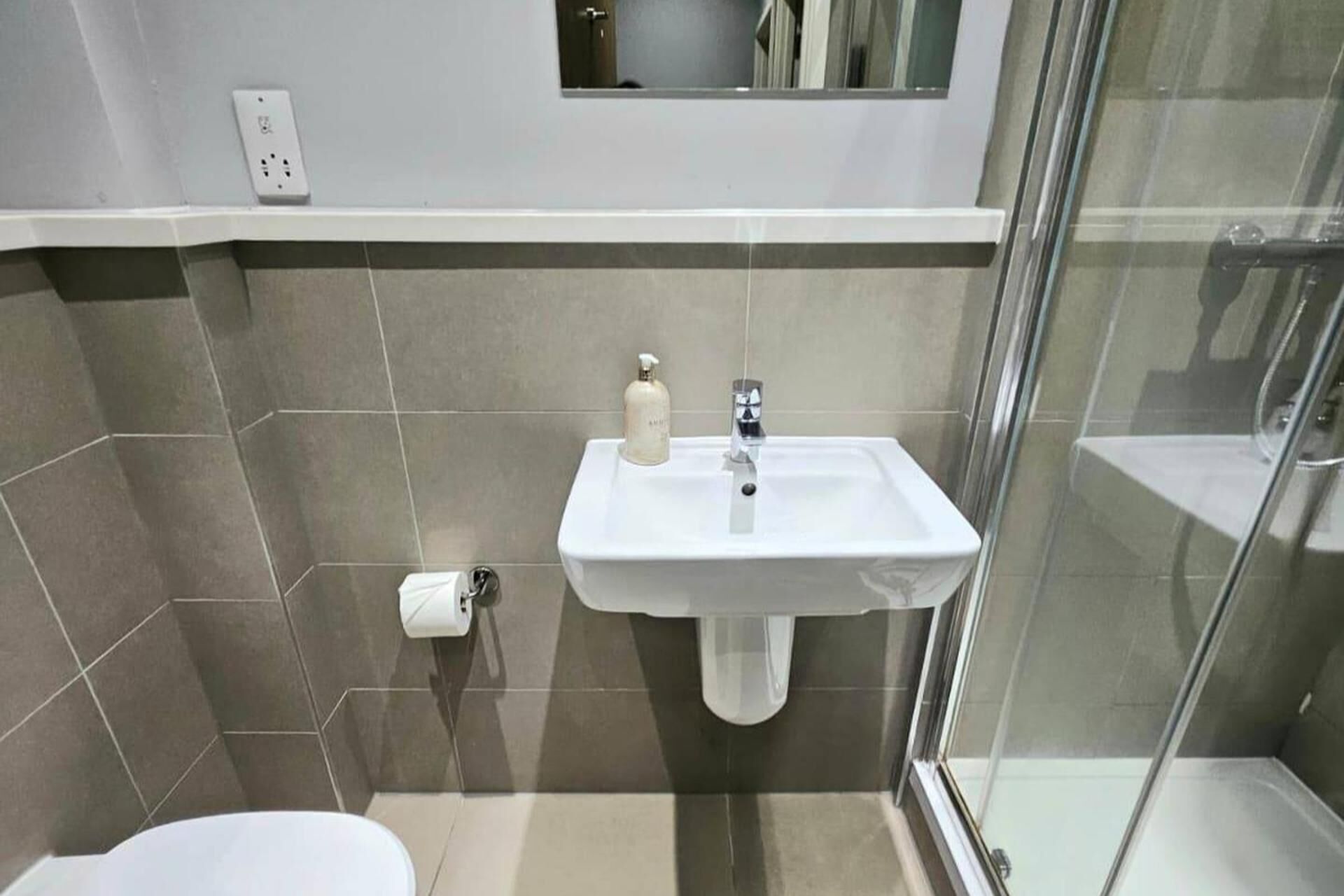 A bathroom with a white sink, a toilet, and a glass shower enclosure.