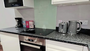 Eine Küche mit schwarzem Arbeitsplatz, einem Einbauofen, einer Mikrowelle, einem Toaster und einem Wasserkocher.