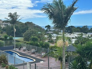 A pool area with lounge chairs and a sign indicating pool hours. - Sunrise Ocean Views + Pool | 3 Bed Coastal Retreat, (Red Head)