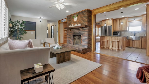 A modern living room with a fireplace, a dining area, and a kitchen with wooden cabinets and stainless steel appliances. - The Nook on the Farm—Pool • Hot Tub • Games (Pataskala)