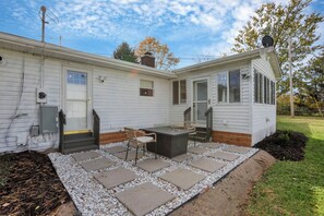 A mobile home with a patio area featuring a table and chairs, a small deck, and a garden bed. - The Nook on the Farm—Pool • Hot Tub • Games (Pataskala)