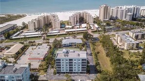 Et kysthotelkompleks bestående af flere bygninger, med en strand i baggrunden og en parkeringsplads.