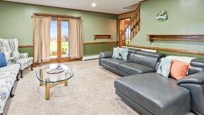 Ein Wohnzimmer mit einer Couch, einem Glastisch und Blick auf eine grüne Rasenfläche durch eine Glasschiebetür.