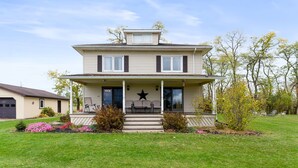 Ein zweistöckiges Haus mit Veranda, einer Sternenverzierung und einem kleinen Garten.