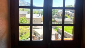 A wooden door with six glass panes, each offering a view of a rural village with stone buildings and greenery. - Country House with stunning views near Porte-Puymorens and Andorra (Carol)