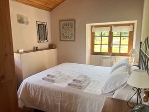 A bedroom with a bed, towels, a window, and a wall-mounted light fixture. - Country House with stunning views near Porte-Puymorens and Andorra (Carol)