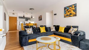 Ein modernes Wohnzimmer mit einer Eckcouch, einem Couchtisch und einer Küche im Hintergrund.