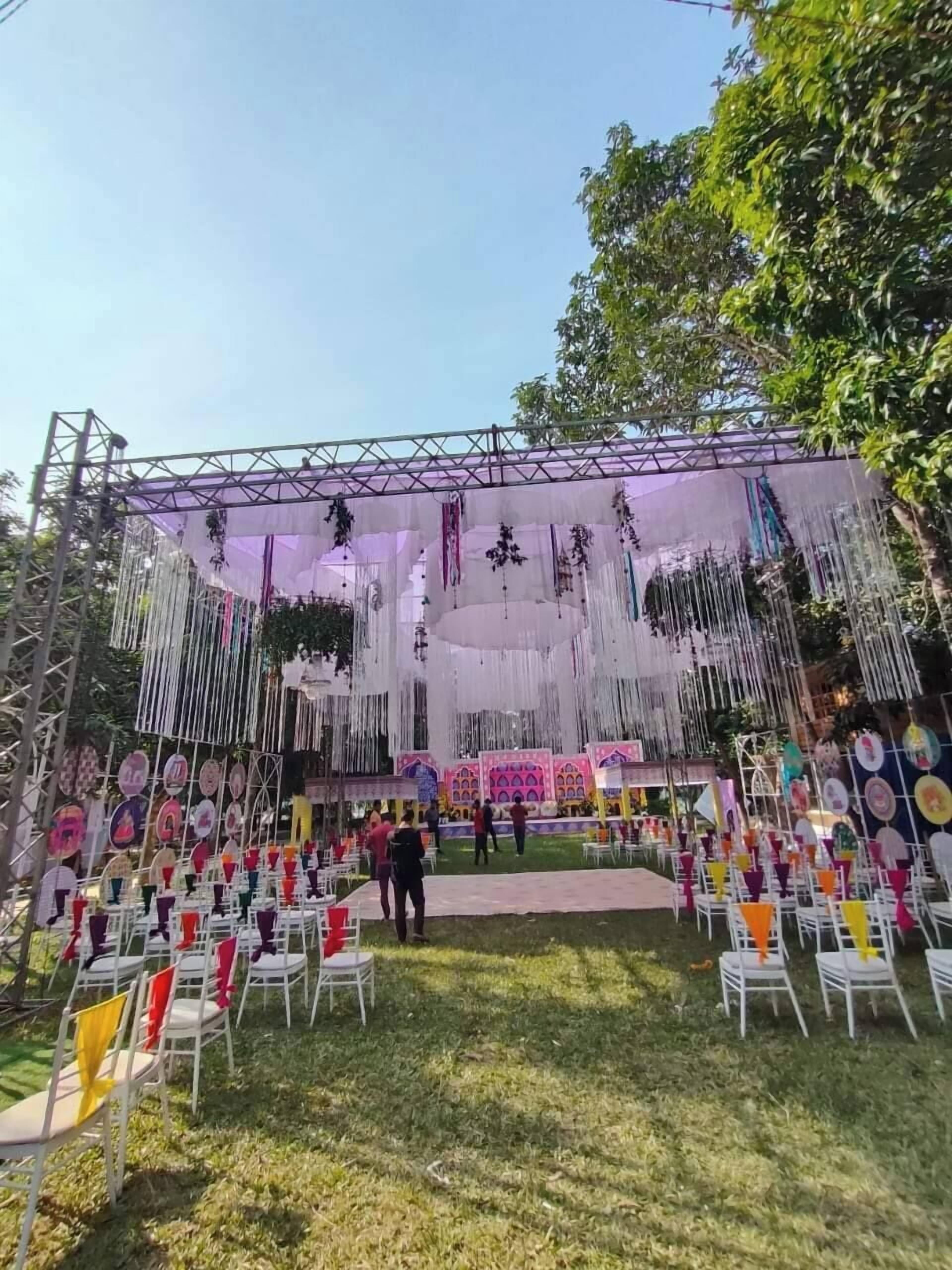 An outdoor event stage with a metal frame, hanging decorations, and a backdrop.