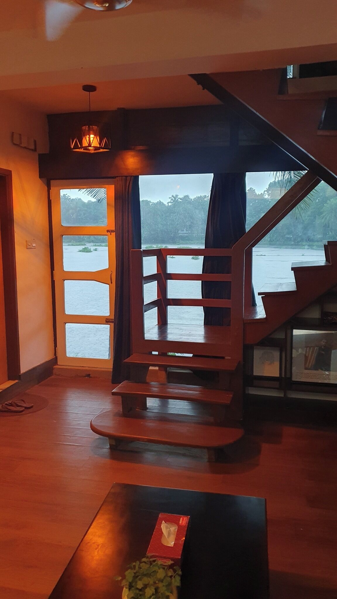 A wooden staircase leading to a balcony with a view of water and trees.