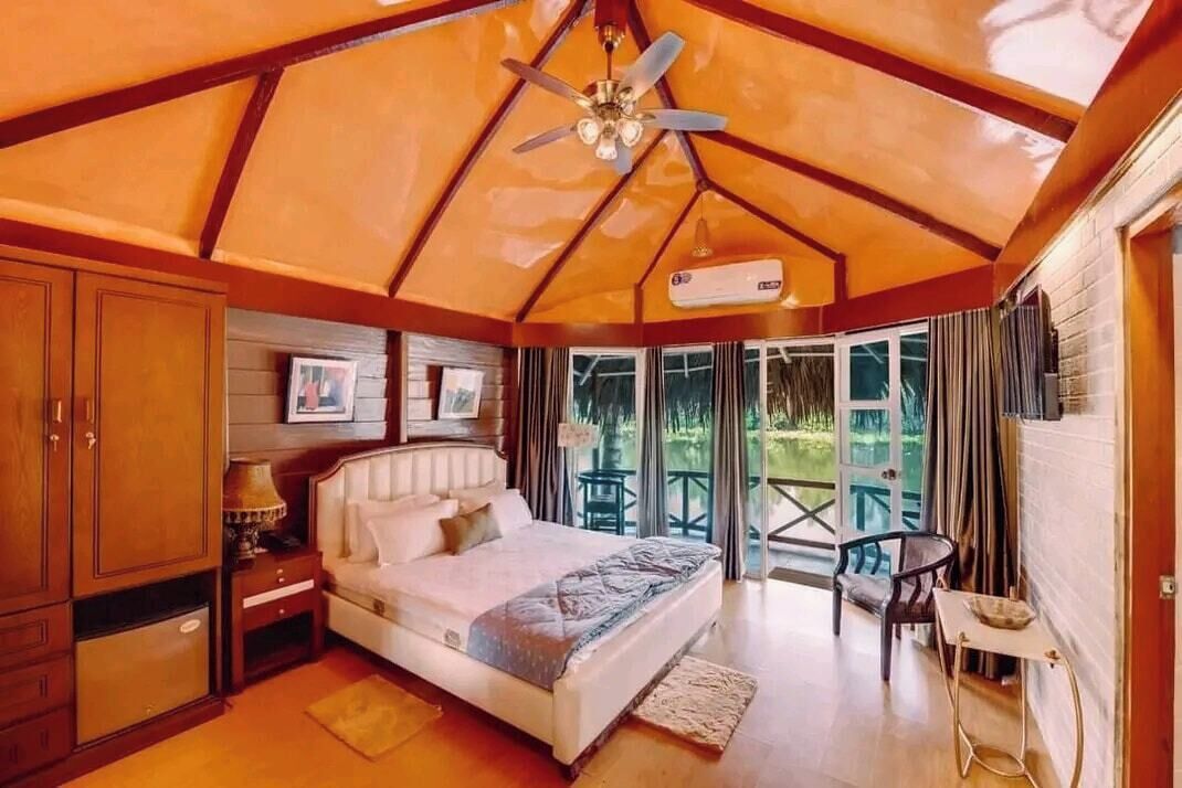 A bedroom with a bed, a nightstand, a ceiling fan, a window, and a balcony.