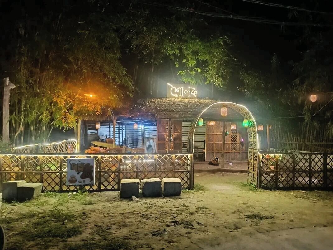 A building with a sign, a fence, and a bench.
