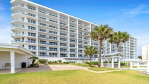 Un hotel de varios pisos con balcones, un patio cubierto y palmeras.