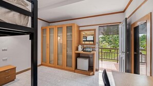 Ein Zimmer mit Etagenbett, Holzschränken, einem kleinen Kühlschrank und einem Esstisch.