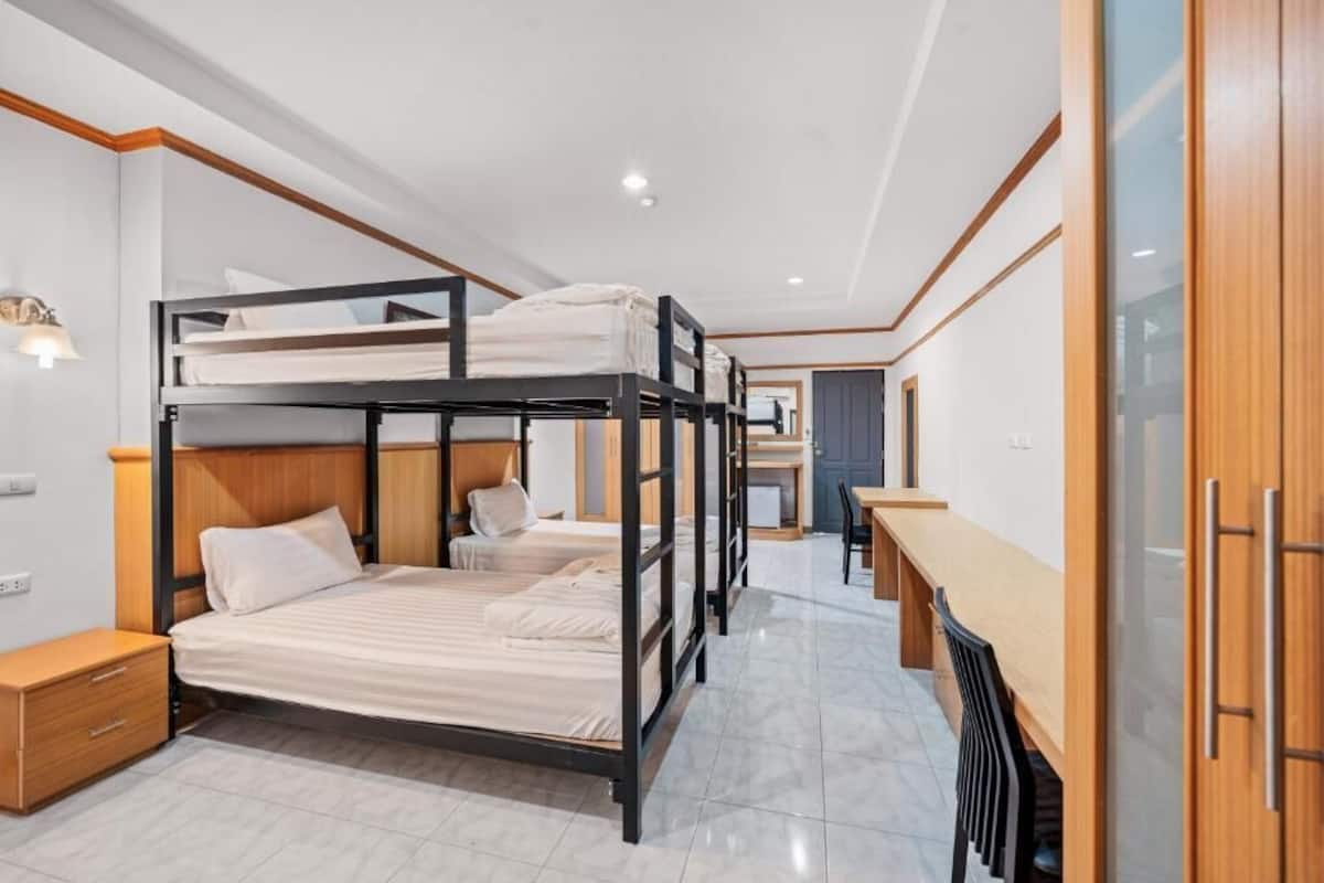 A bunk bed room with a desk and chair, a small table, and a cabinet.