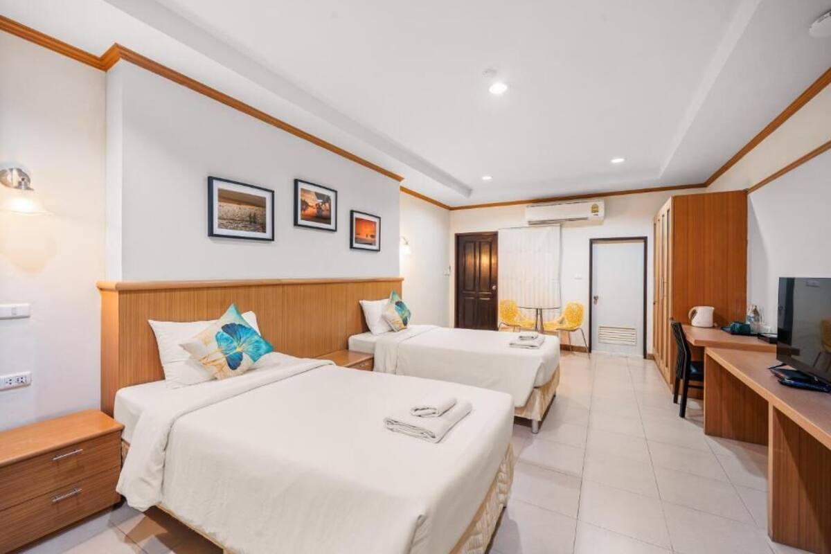 A hotel room with two beds, a desk, a chair, and a TV.