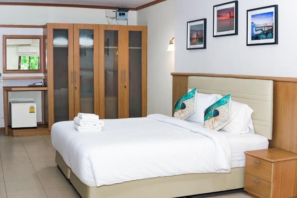 Ein Hotelzimmer mit Bett, Kleiderschrank, Schreibtisch mit Computer und kleinem Kühlschrank.