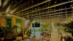 An indoor dining area with wooden tables and chairs, a staircase, and hanging string lights. - My Stay 1 Le Van Tam (Xuan Huong - Da Lat)