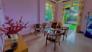 A dining area with a table and chairs, a vase with red berries, and a view of the outside. - My Stay 1 Le Van Tam (Xuan Huong - Da Lat)