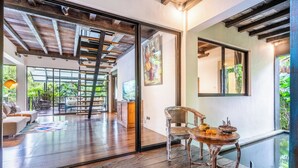 Un intérieur moderne avec une porte vitrée donnant sur un balcon, une table en bois décorée de fleurs et un fauteuil en osier.