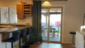 Una cocina con barra, una mesa de comedor y vistas a un patio exterior a través de un ventanal.