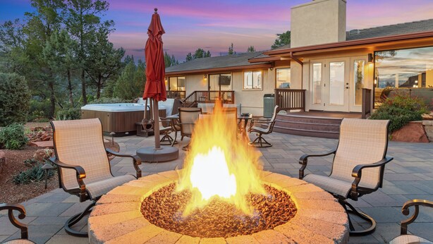 Eine Terrasse mit Feuerstelle, Sitzgelegenheiten im Freien und einem Gebäude im Hintergrund.