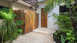 A modern house with a wooden fence, a concrete pathway, and lush greenery. - Casa Wayra Tulum - Boutique Condos (Tulum)
