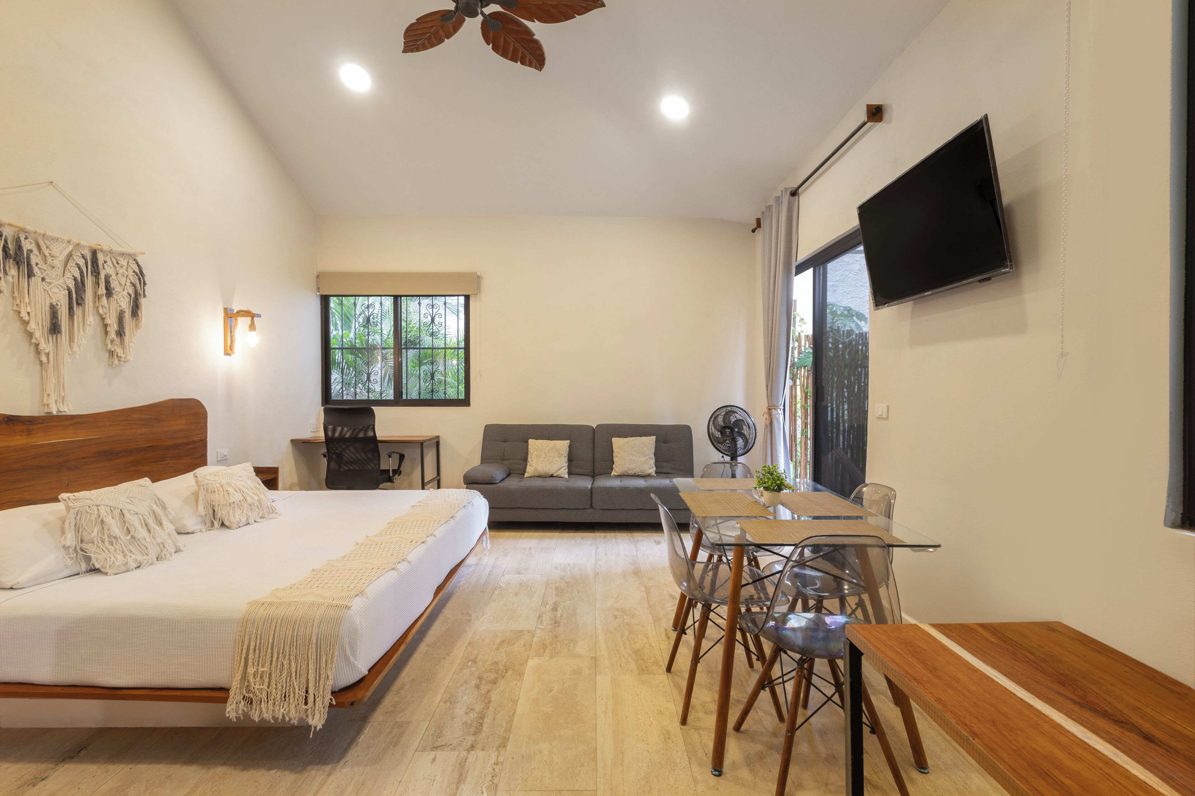 A modern bedroom with a large bed, a dining table, and a sofa.