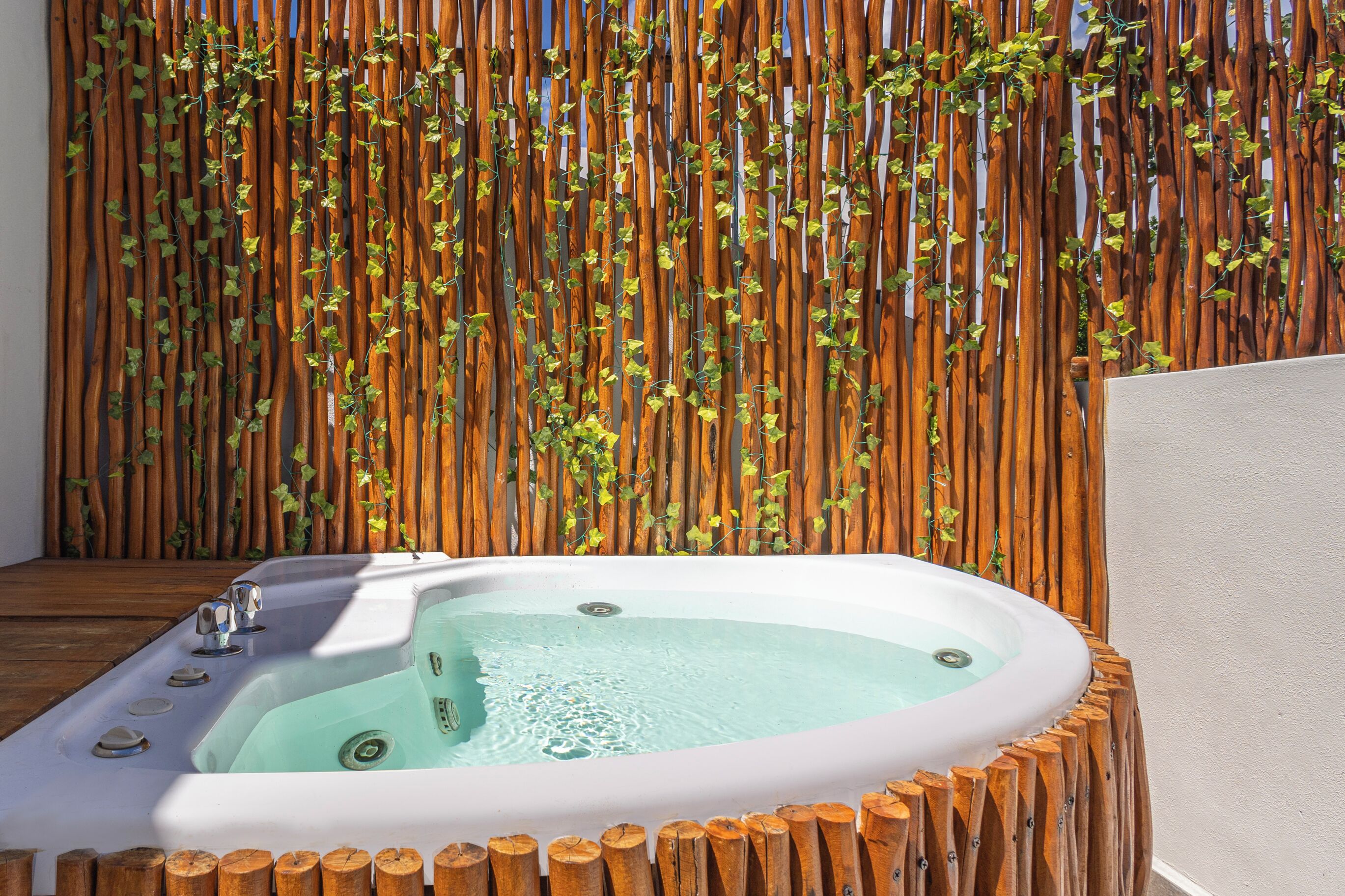 Un espace de détente avec un jacuzzi entouré de rondins de bois et un mur en bambou.