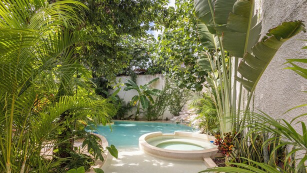 A circular hot tub surrounded by lush tropical plants and a clear pool. - Casa Wayra Tulum - Boutique Condos (Tulum)