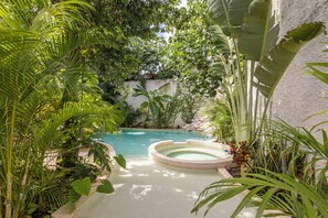 Tinaco circular rodeado de exuberante vegetación tropical y una piscina cristalina.