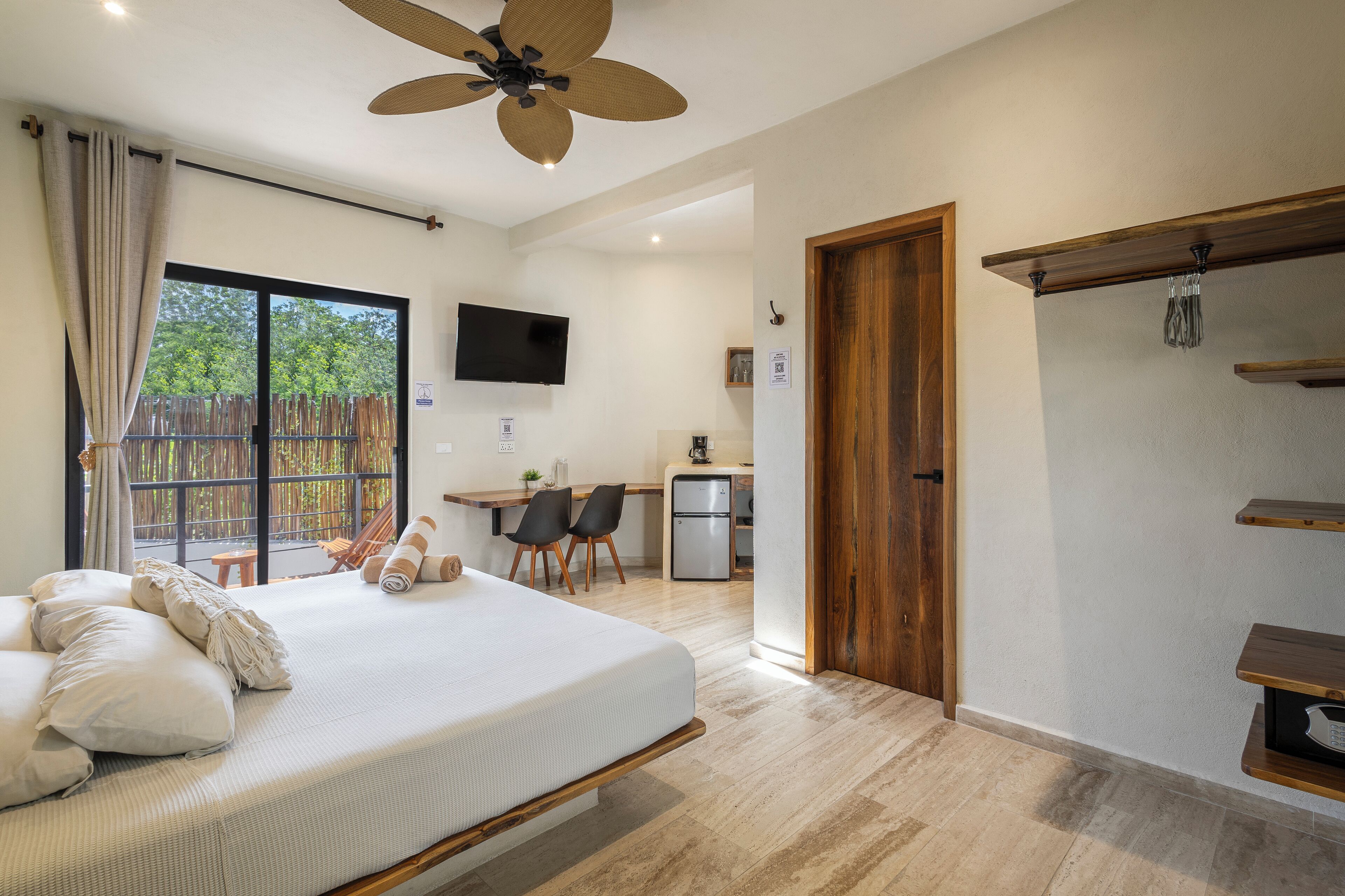 A bedroom with a bed, a desk, and a TV in the background.