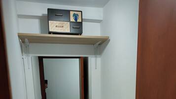 Een kleine badkamer met toilet, een spiegel en een plank met decoratieve objecten.