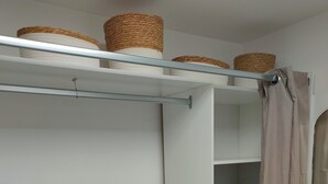 Un dressing accessible sans porte, doté d’étagères ouvertes, d’une tringle à vêtements et d’un rideau de douche.