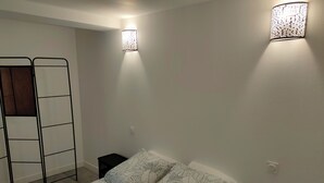 Une chambre à coucher avec un lit, une échelle et deux lampes fixées au mur.