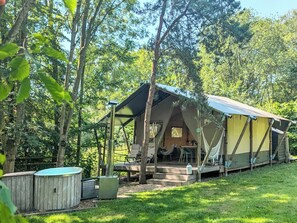 Eine Zelthütte mit Veranda, Sitzgelegenheiten im Freien und einem Whirlpool.