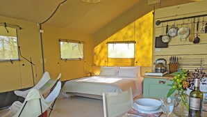 A cozy bedroom with a bed, a chair, a table with a bottle, and a kitchen area with utensils. - The Apple Bobber - UKC7130 (Cratfield, near Laxfield)