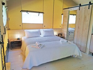 Ein Zimmer mit einem Bett, einem Nachttisch mit Lampe, einem Holzschrank und einem Fenster.